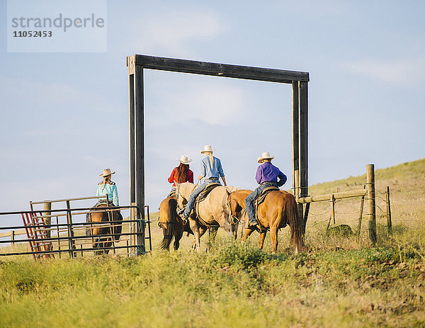 Cowboy und Cowgirls reiten auf einer Ranch