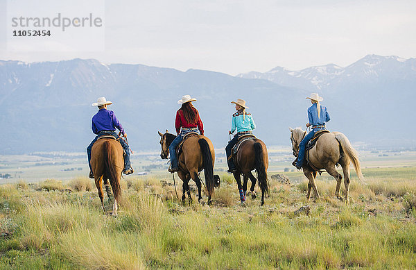 Cowboy und Cowgirls reiten auf einer Ranch