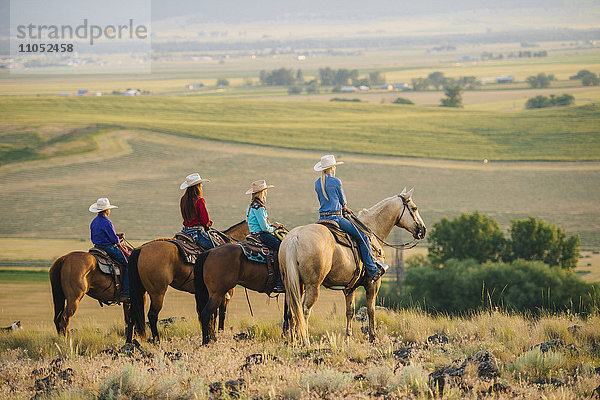 Cowboy und Cowgirls auf dem Pferderücken bewundern ländliche Landschaft