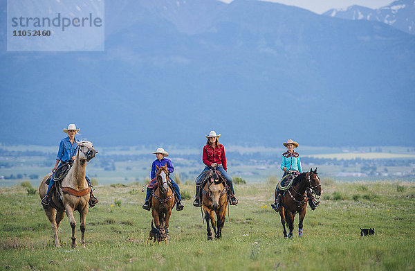 Cowboy und Cowgirls reiten auf einer Ranch