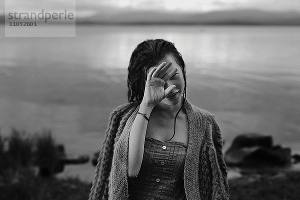 Kaukasisches Mädchen mit nassen Haaren am See  die das Gesicht verdecken