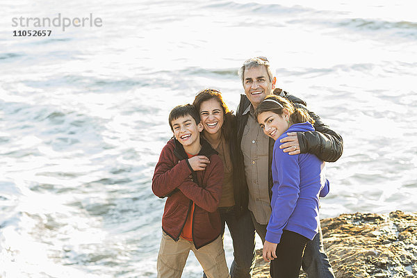 Familie umarmt in der Nähe von Meereswellen