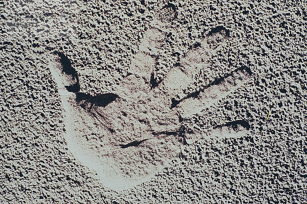 Abdruck einer menschlichen Hand mit gespreizten Fingern auf Sand