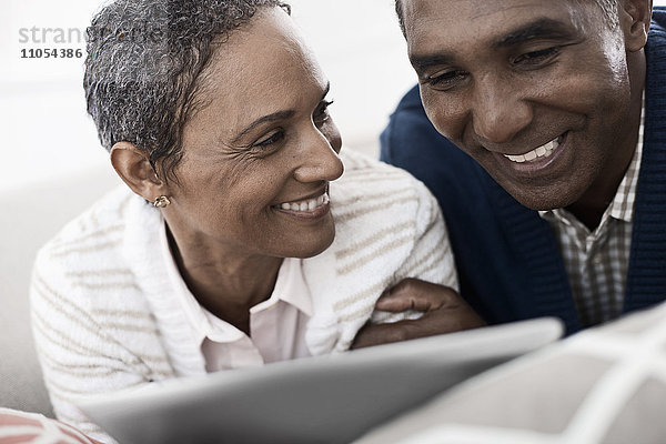 Ein Paar  Mann und Frau  auf dem Bauch liegend  teilen sich ein digitales Tablett.