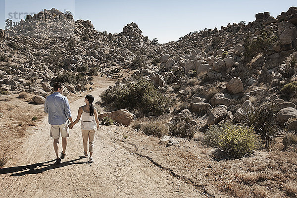 Zwei Personen  ein Paar  das durch eine felsige Landschaft entlang eines Weges geht.