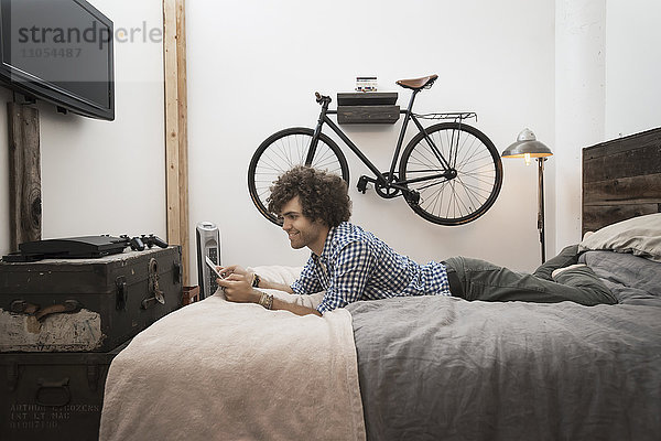 Loft-Wohnen. Ein Fahrrad  das an der Wand hängt. Ein Mann  der ein digitales Tablett benutzt.