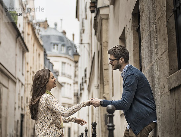 Ein Mann und eine Frau halten sich auf einer Straße in der Stadt an den Händen.