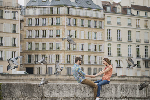 Ein Paar  Mann und Frau  die auf der Brüstung einer Brücke über die Seine sitzen.