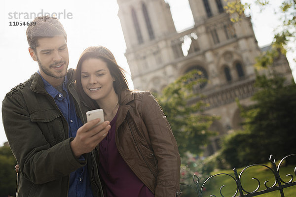 Zwei Menschen  ein Paar  das eng beieinander steht und sich vor der historischen Kathedrale Notre Dame in Paris niederlässt.