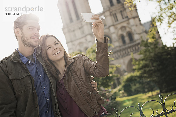 Zwei Menschen  ein Paar  das eng beieinander steht und sich vor der historischen Kathedrale Notre Dame in Paris niederlässt.