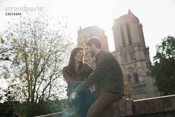 Ein romantisch gestimmtes Paar  Seite an Seite  die Arme umeinander gelegt  vor der Kathedrale Notre Dame in Paris.