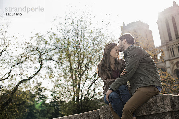 Ein romantisch gestimmtes Paar  Seite an Seite  die Arme umeinander gelegt  vor der Kathedrale Notre Dame in Paris.
