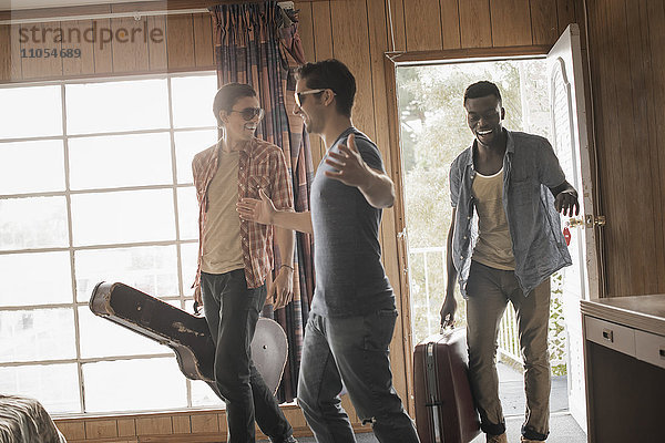 Freunde  drei junge Männer in einem Motelzimmer  mit Koffern und einer Gitarre.