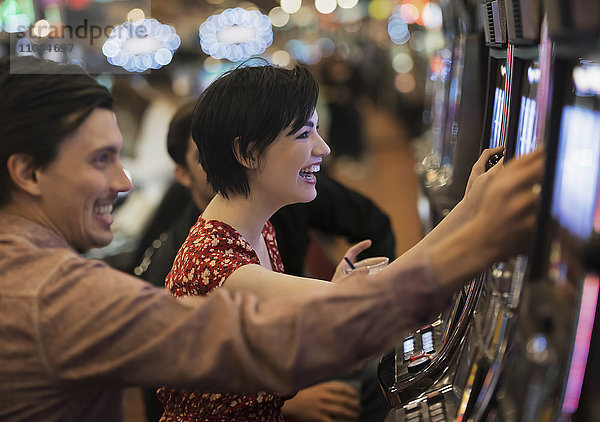 Zwei Personen  ein junger Mann und eine Frau  spielen in einem Kasino an den Spielautomaten.