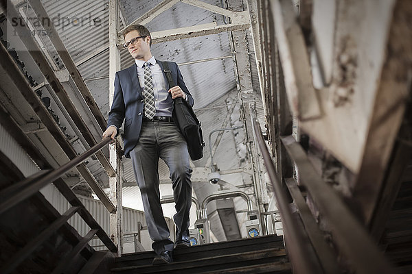 Ein Arbeitstag. Ein Geschäftsmann im Arbeitsanzug und mit Krawatte  der in einem öffentlichen Raum die Treppe hinuntergeht.
