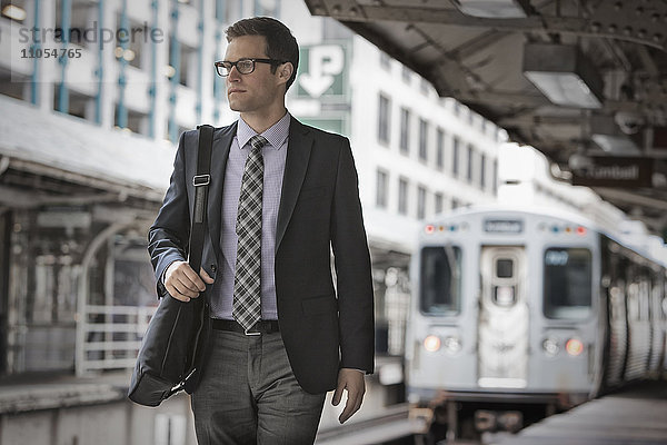 Ein Arbeitstag. Geschäftsmann in Arbeitsanzug und Krawatte auf dem Bahnsteig eines Bahnhofs.