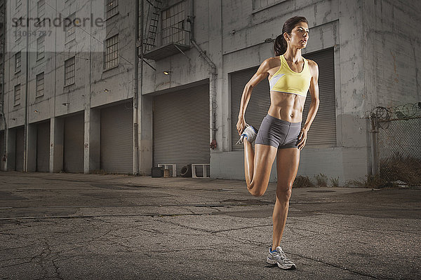 Eine Frau in Laufbekleidung  Korboberteil und Shorts  die ihren Körper streckt und sich auf einen Lauf vorbereitet oder sich nach dem Training abkühlt.