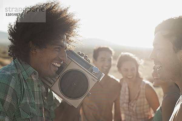 Gruppe junger Menschen  Männer und Frauen  die mit einem Ghettoblaster auf der offenen Straße gehen.