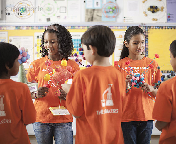 Eine Gruppe von Mädchen und Jungen  die das T-Shirt des Science Club tragen und Molekularstrukturmodelle anfertigen.