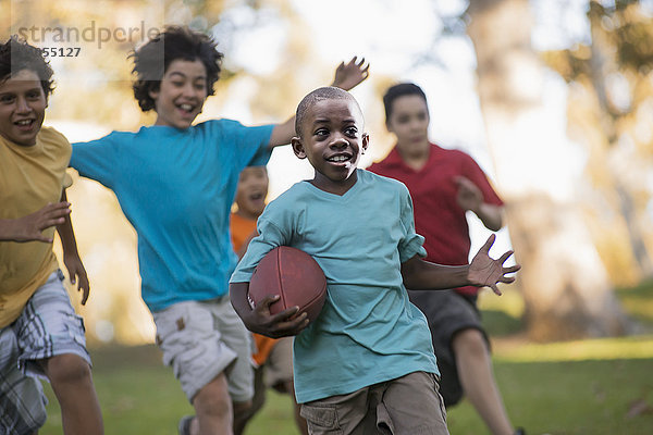 Kinder  die im Sommer im Freien spielen  einer läuft mit einem Ball.