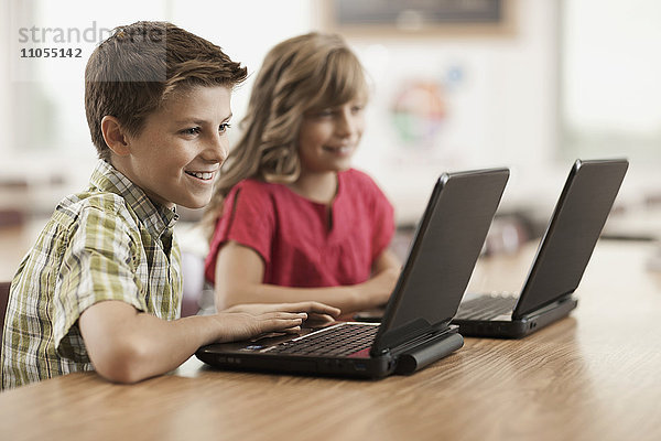 Zwei Kinder saßen in der Klasse mit Laptop-Computern an den Schreibtischen.