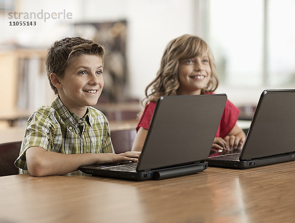 Zwei Kinder saßen in der Klasse mit Laptop-Computern an den Schreibtischen.