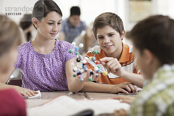 Eine Gruppe von Studenten sitzt in einer Lektion am Schreibtisch und betrachtet eine Molekularstruktur.
