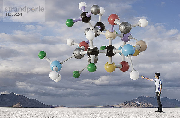 Ein Teenager  der nach oben auf eine Molekularstruktur in der Luft über ihm schaut.