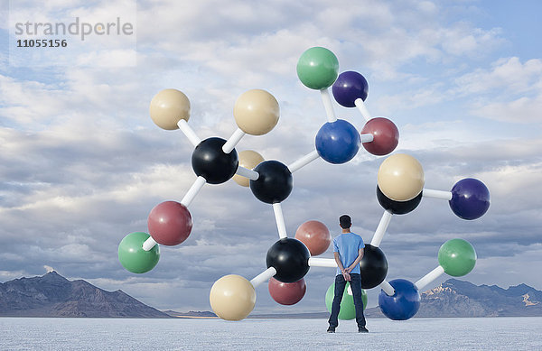 Ein Teenager  der nach oben auf eine große Molekularstruktur in der Luft über ihm schaut.