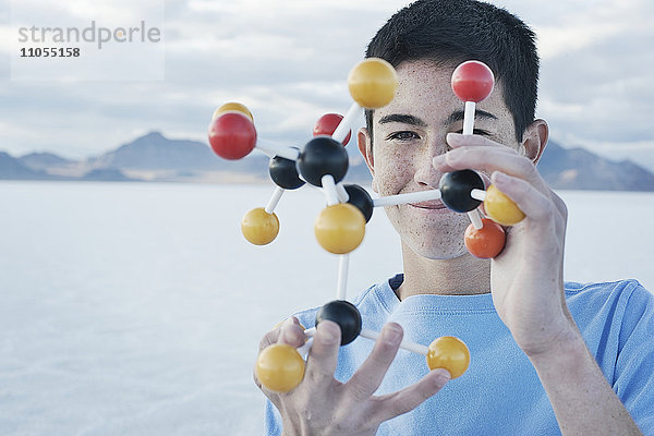 Ein Jugendlicher  der eine Molekularstruktur in der Hand hält und sie untersucht.
