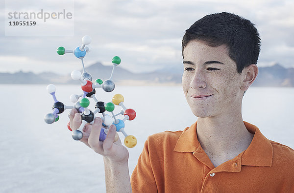 Ein Jugendlicher hält ein molekulares Modell in der Hand  in dem verschiedenfarbige Kugeln Atome darstellen.