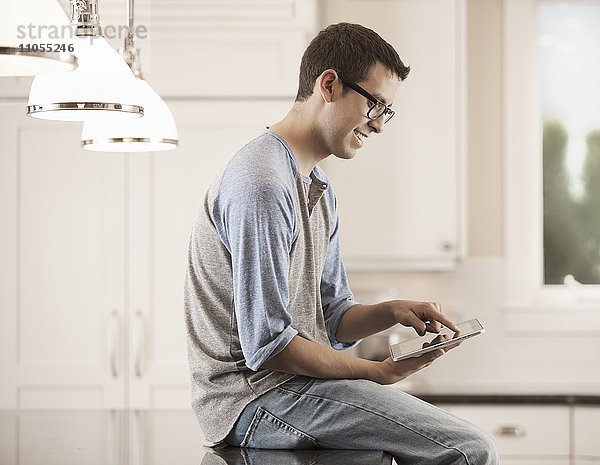 Ein Mann sitzt zu Hause und benutzt ein digitales Tablett.