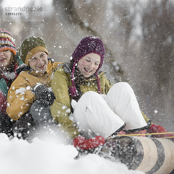 Drei Kinder saßen auf einem Schlitten  der einen Schneehang hinunterrutschte.