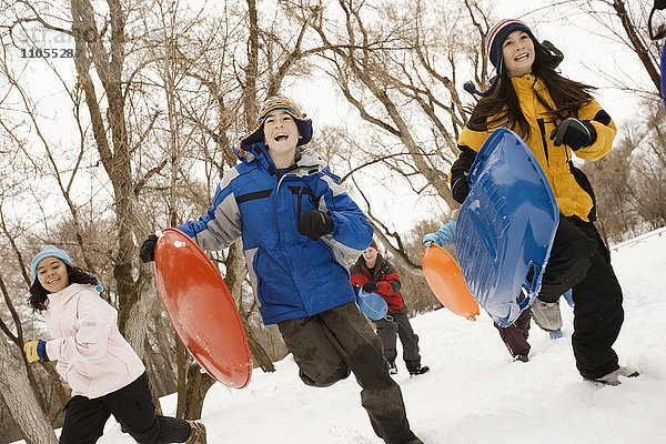 Eine Gruppe von Kindern  Jungen und Mädchen  rannte mit Schlitten über den Schnee.