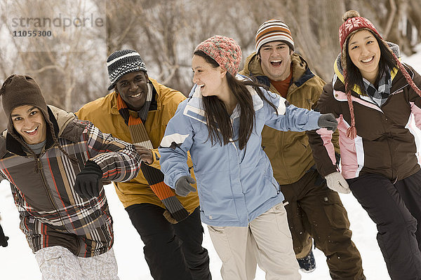 Fünf junge Leute  Männer und Frauen  rennen über den Schnee.