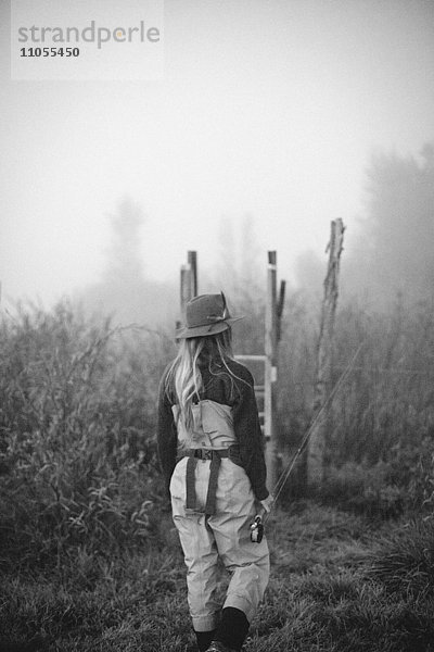 Eine Frau  die auf einem Holzstil im Nebel steht.