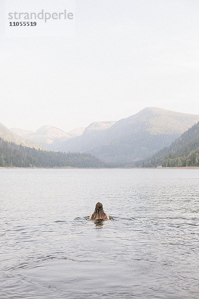 Eine Frau  die im Wasser eines Sees schwimmt.