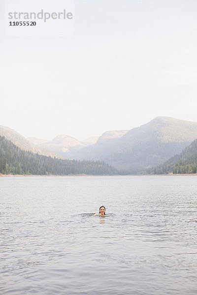 Eine Frau  die im Wasser eines Sees schwimmt.