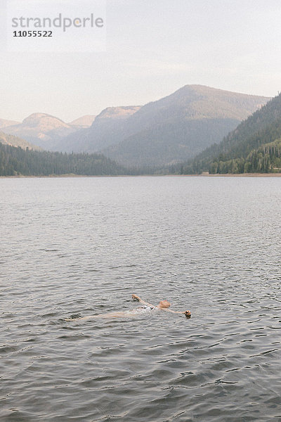 Eine Frau  die im Wasser eines Sees schwimmt.