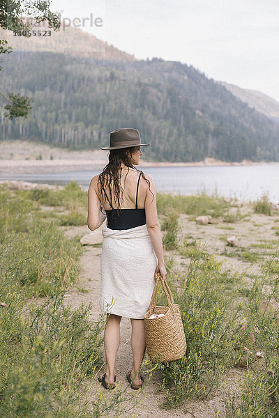 Eine in ein Handtuch gewickelte Frau  die einen Weg an einem See entlang geht.