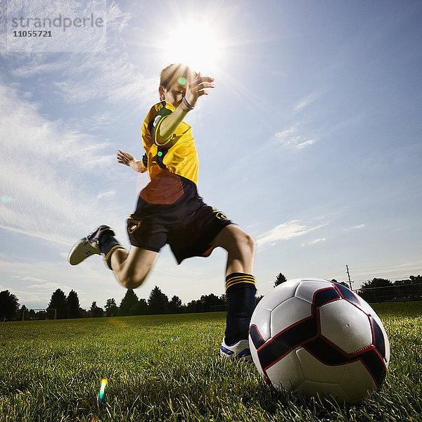 Ein Fußballspieler  ein Junge  der sich darauf vorbereitet  einen Fußball zu kicken.
