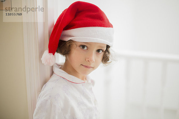 Ein junges Mädchen mit Weihnachtsmannmütze am Weihnachtsmorgen.