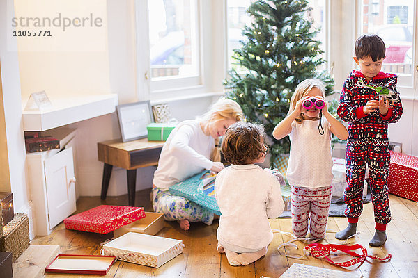 Eine Mutter und drei Kinder öffnen am Weihnachtsmorgen Geschenke.