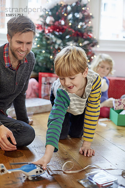 Ein Mann und zwei Kinder finden und packen am Weihnachtstag Geschenke aus.