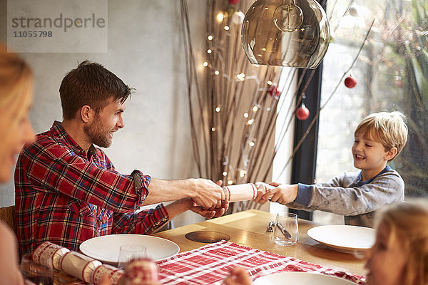 Eine vierköpfige Familie  zwei Erwachsene und zwei Kinder  saß zur Weihnachtszeit um einen Tisch herum und zogen Kekse.