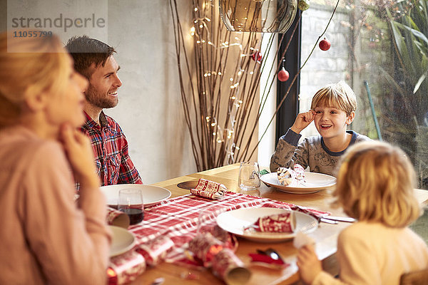 Eine vierköpfige Familie  zwei Erwachsene und zwei Kinder  saß zur Weihnachtszeit um einen Tisch herum und zogen Kekse.