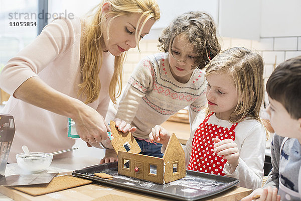 Eine Frau und drei Kinder beim Bau eines Hauses für gebackene Lebkuchen.