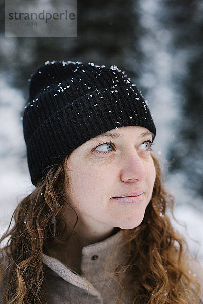 Eine Frau mit schwarzem Hut staubte im Freien Schnee ab.