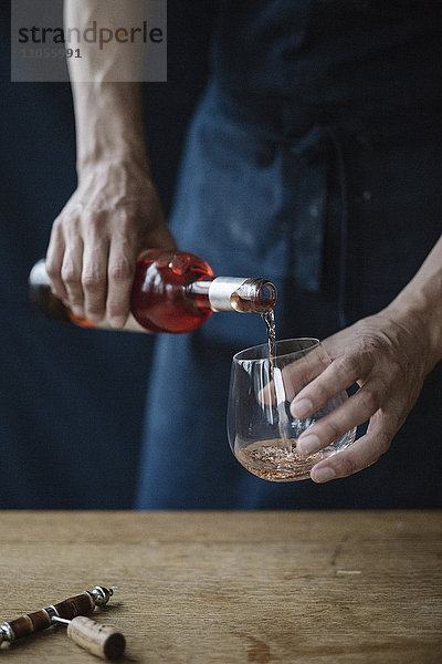 Eine Frau gießt ein Getränk aus einer Flasche ein.