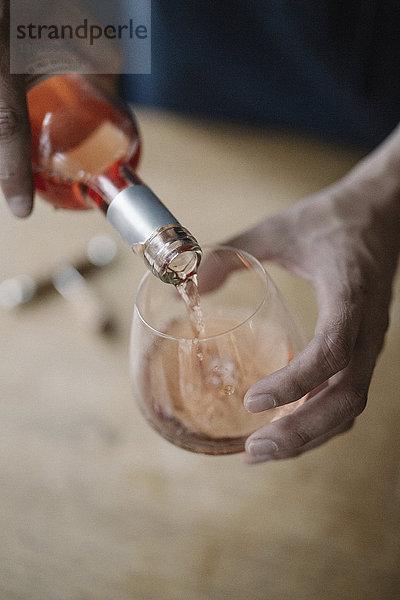 Eine Frau schenkt ein Getränk aus einer Flasche Wein ein.